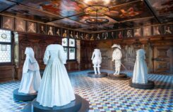 An exhibition of historical white clothing inside a Swiss museum room.