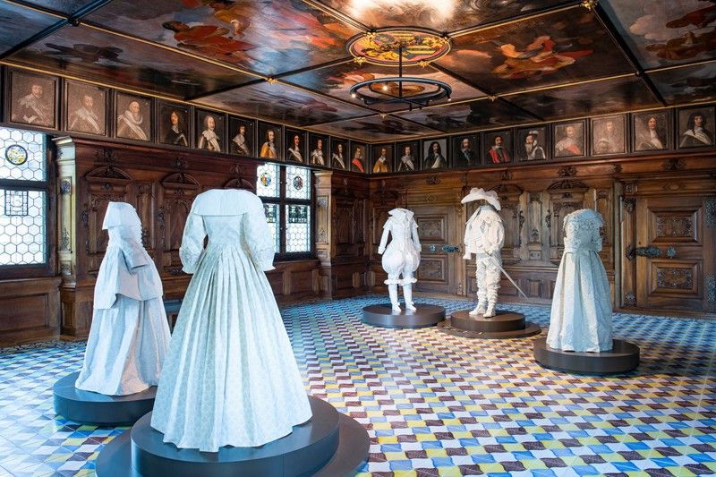 An exhibition of historical white clothing inside a Swiss museum room.